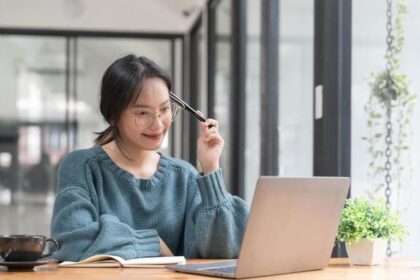 A woman smiling as she takes free online courses on her laptop, symbolizing personal growth.