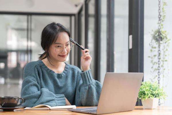 A woman smiling as she takes free online courses on her laptop, symbolizing personal growth.