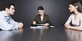 A couple sitting at a table with a mediator, house keys between them